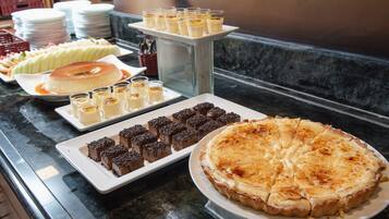 Buffet com diversos doces, incluindo torta, brownies e copinhos de creme.