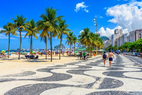 A beachside promenade with palm trees, beach umbrellas, and a tiled walkway. - ibis Rio de Janeiro Santos Dumont (Rio de Janeiro)