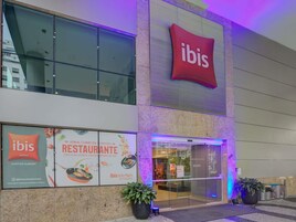 Un edificio moderno con un'insegna 'ibis' ben visibile sopra l'ingresso, ampie finestre e un display digitale.
