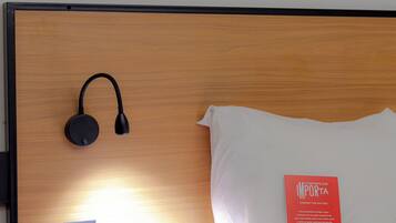 A neatly made bed with a white pillow and a red book titled "COMFORT THAT MATTERS" on the headboard.
