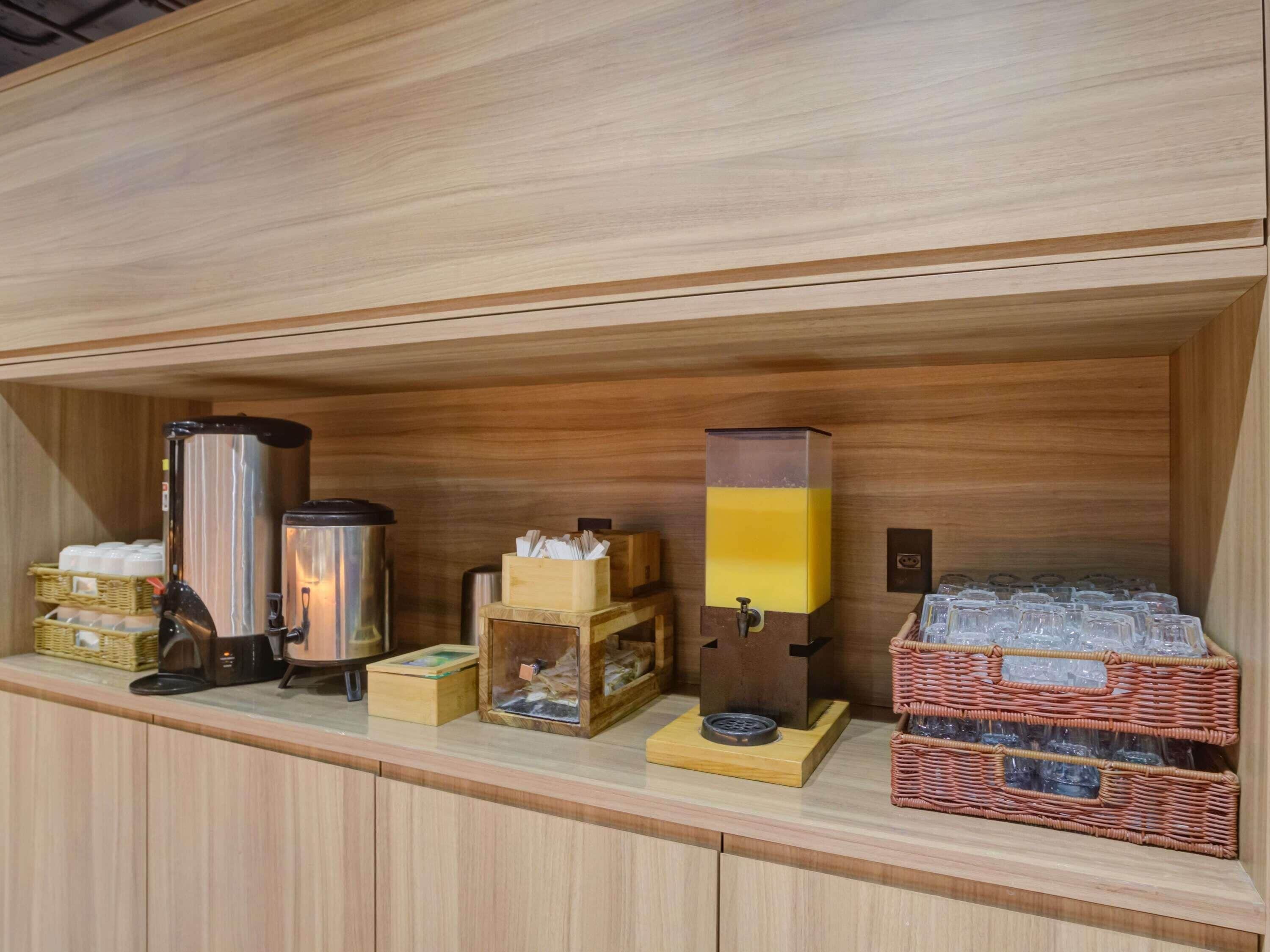 A wooden counter with various amenities including a coffee machine, a water dispenser, and storage baskets.