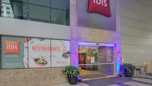 The exterior of a hotel with a prominent 'ibis' sign, a glass entrance, and potted plants in front. - ibis Rio de Janeiro Santos Dumont (Rio de Janeiro)