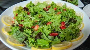 A plate of salad with lettuce, strawberries, and lemon slices.