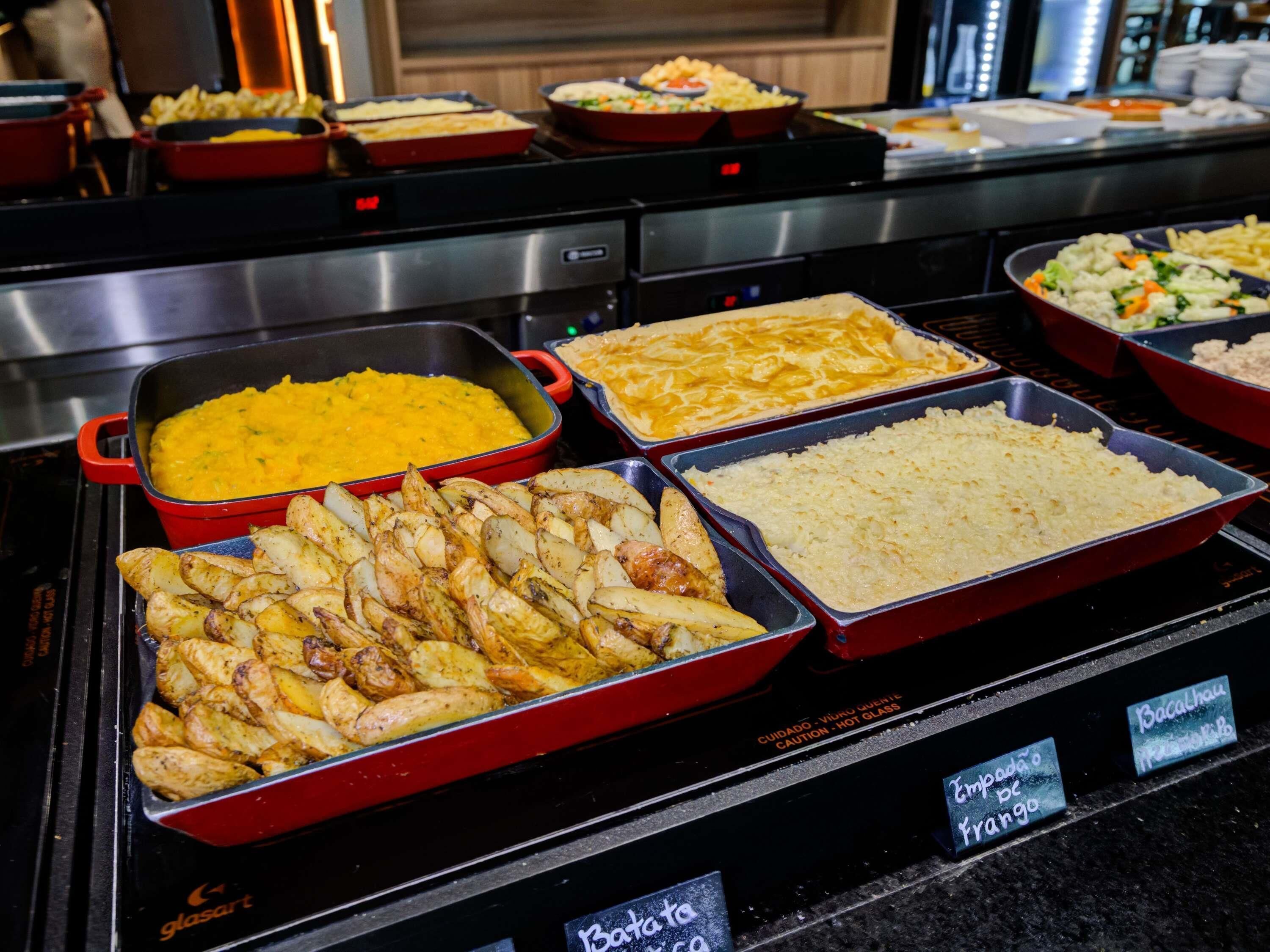 A buffet with various dishes including potatoes, rice, and a yellow dish, likely a curry.