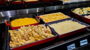 A buffet with various dishes including potatoes, rice, and a yellow dish, likely a curry.