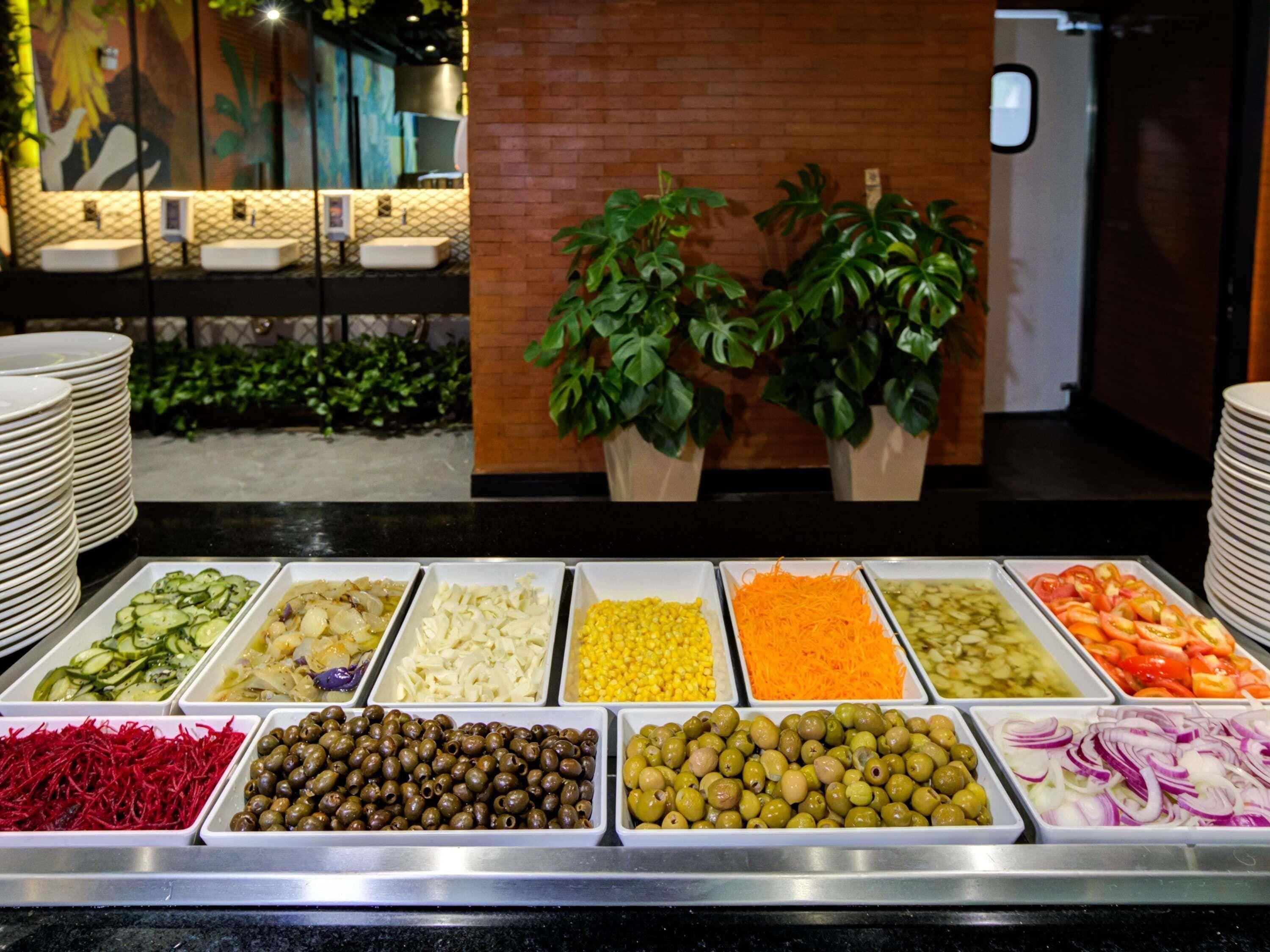 Un bufé con diferentes opciones de comida, una pared de ladrillo y plantas en macetas.
