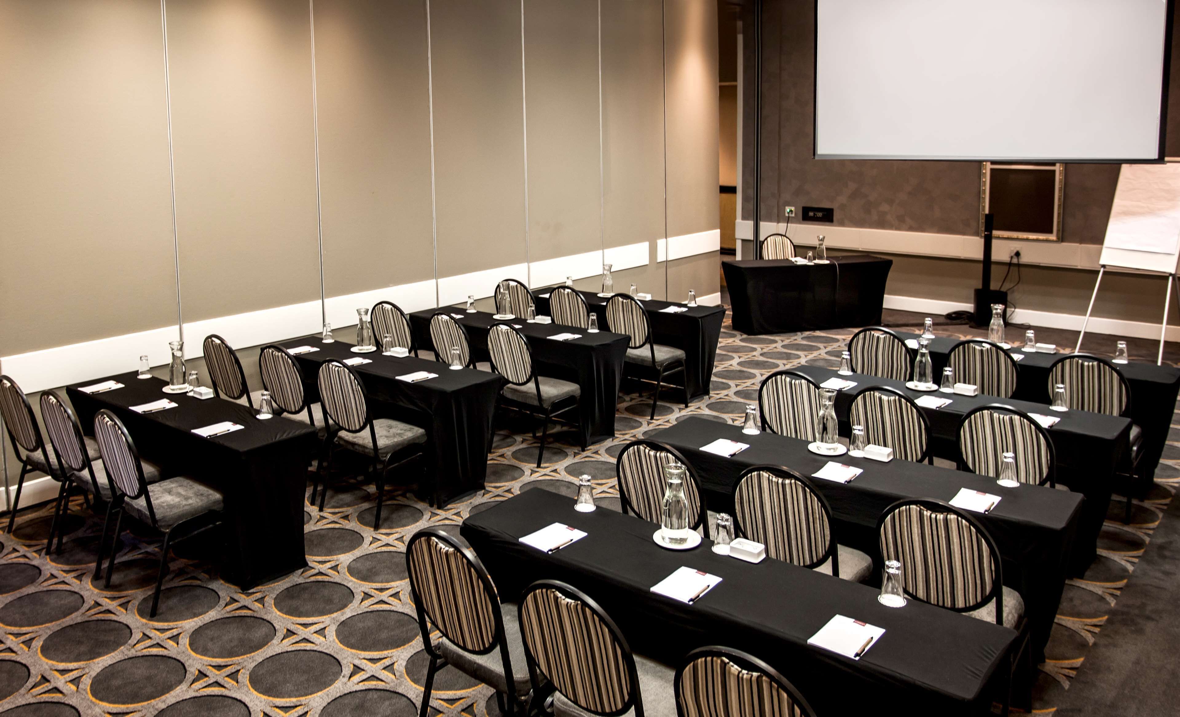 A conference room with multiple tables and chairs, equipped with nameplates, water bottles, and notepads.