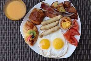 Savor a hearty breakfast with eggs, sausages, bacon, toast, potatoes, and fresh juice.