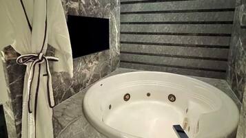 A modern bathroom with a marble floor, a freestanding bathtub, and a robe hanging on a hook.