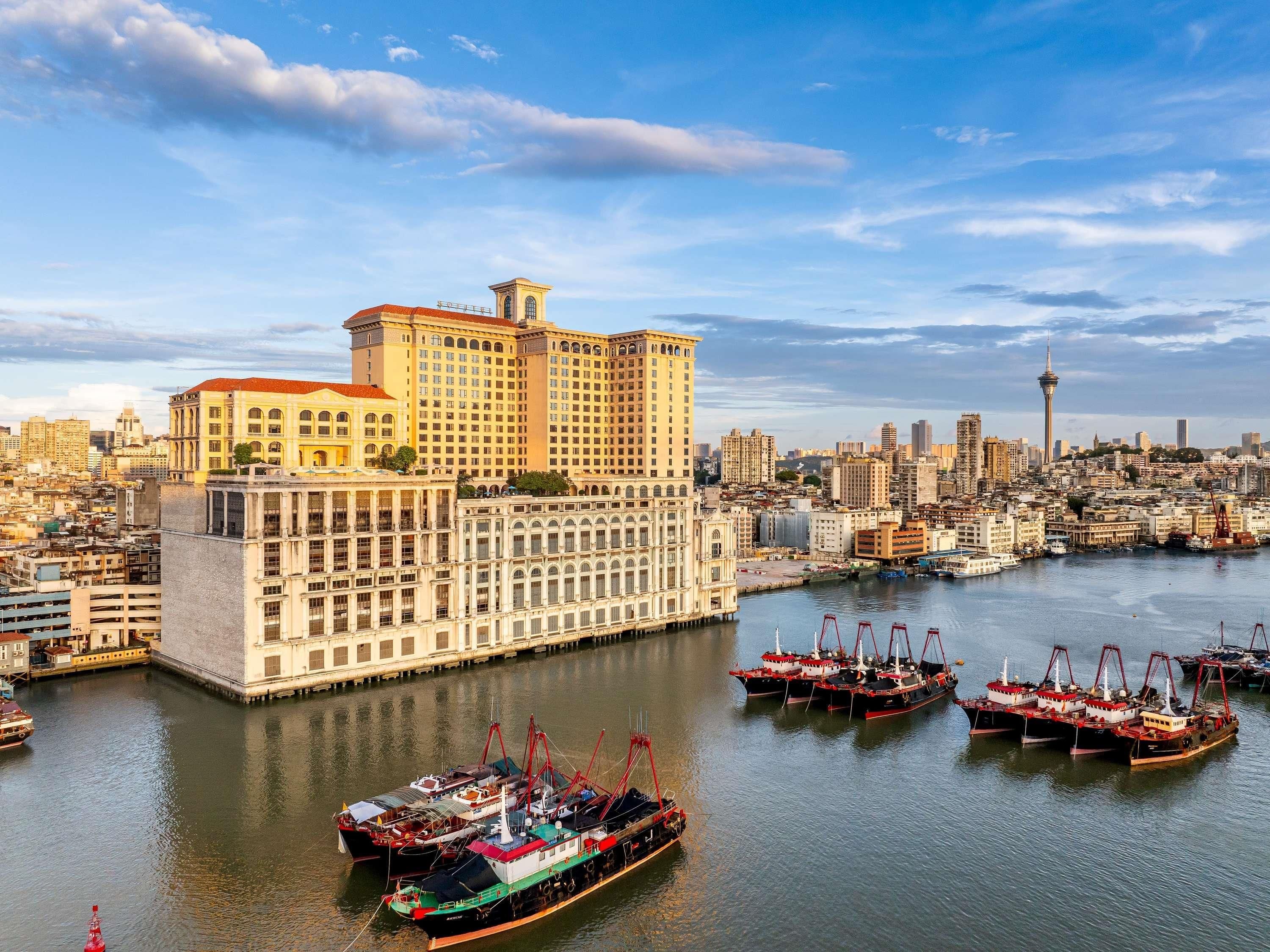 A waterfront hotel with multiple floors, a prominent tower, and a view of the city skyline.