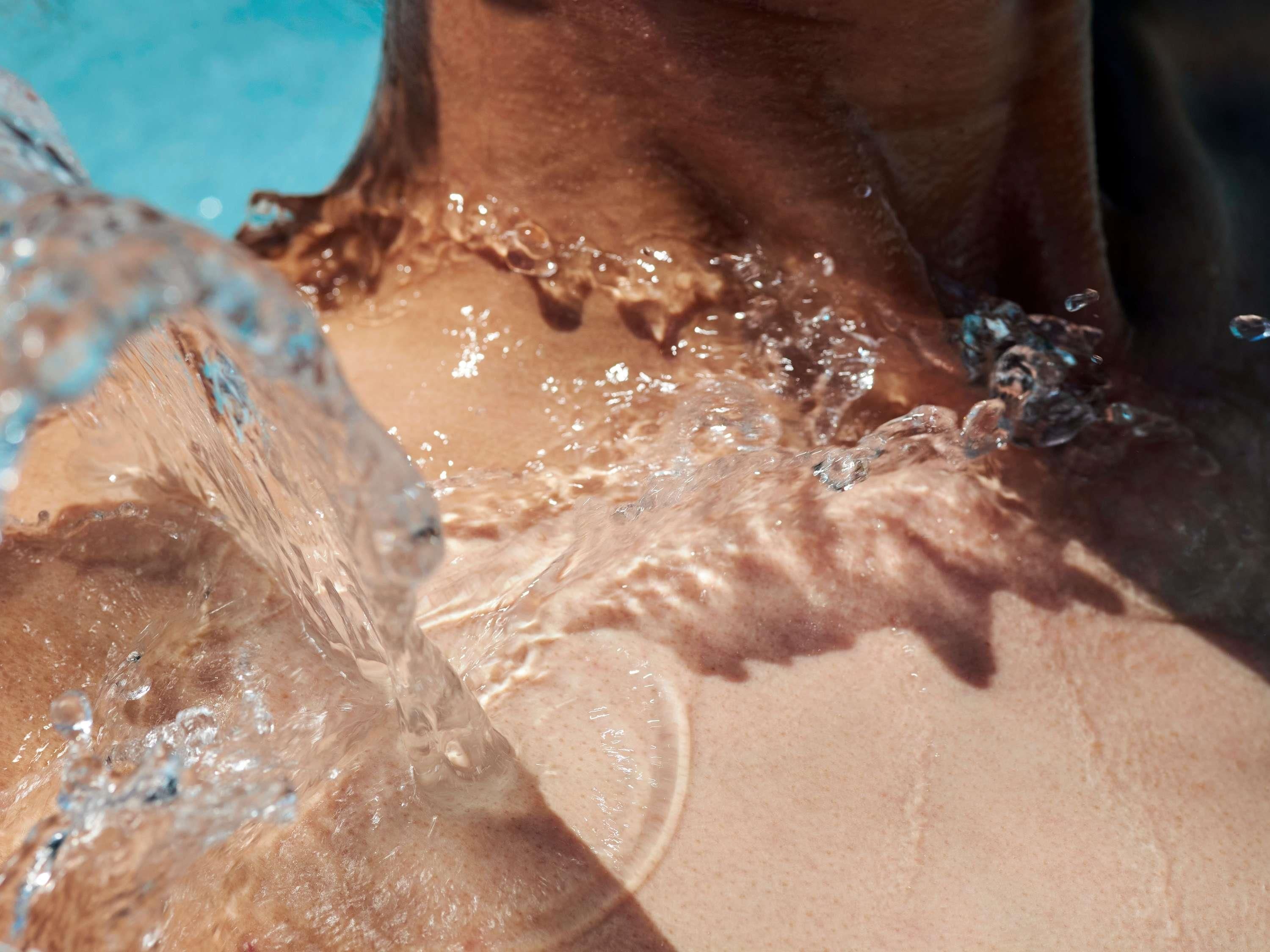 Close-up van iemands huid met waterdruppels, wat een nat oppervlak aangeeft.