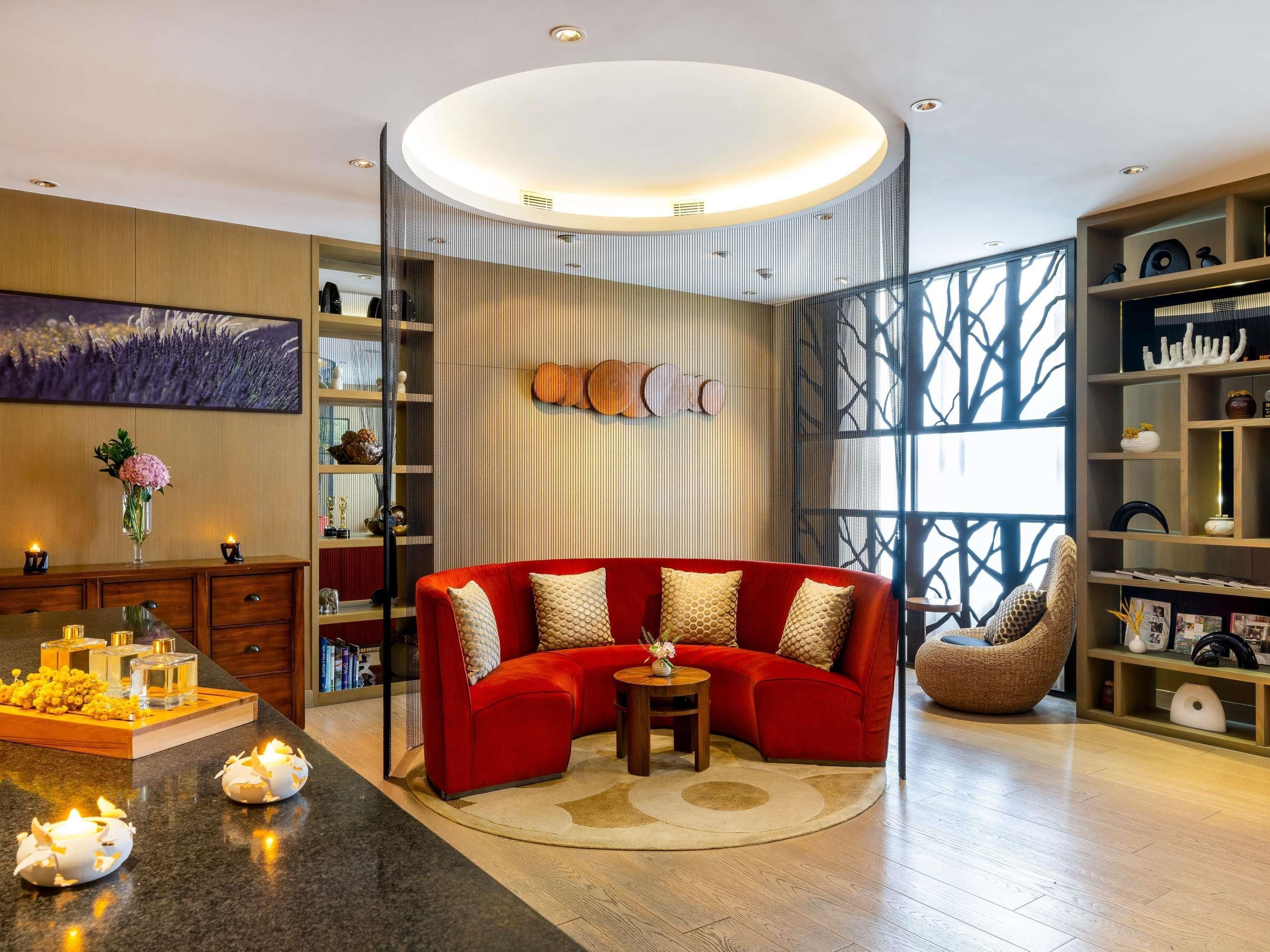 Un salon moderne avec un canapé rouge, une table basse ronde et une bibliothèque.