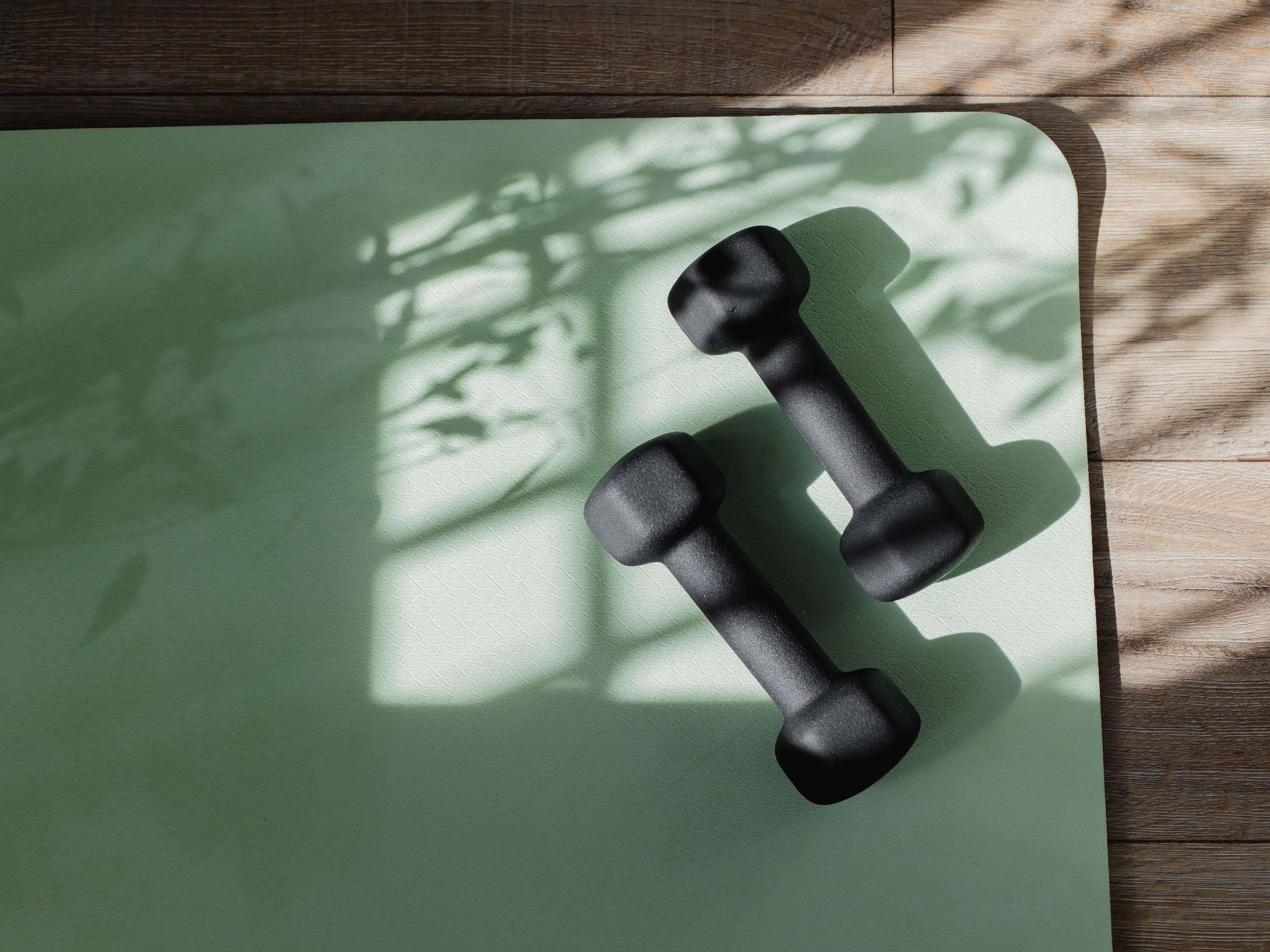 Twee zwarte gewichtsschijven op een groene yogamat.