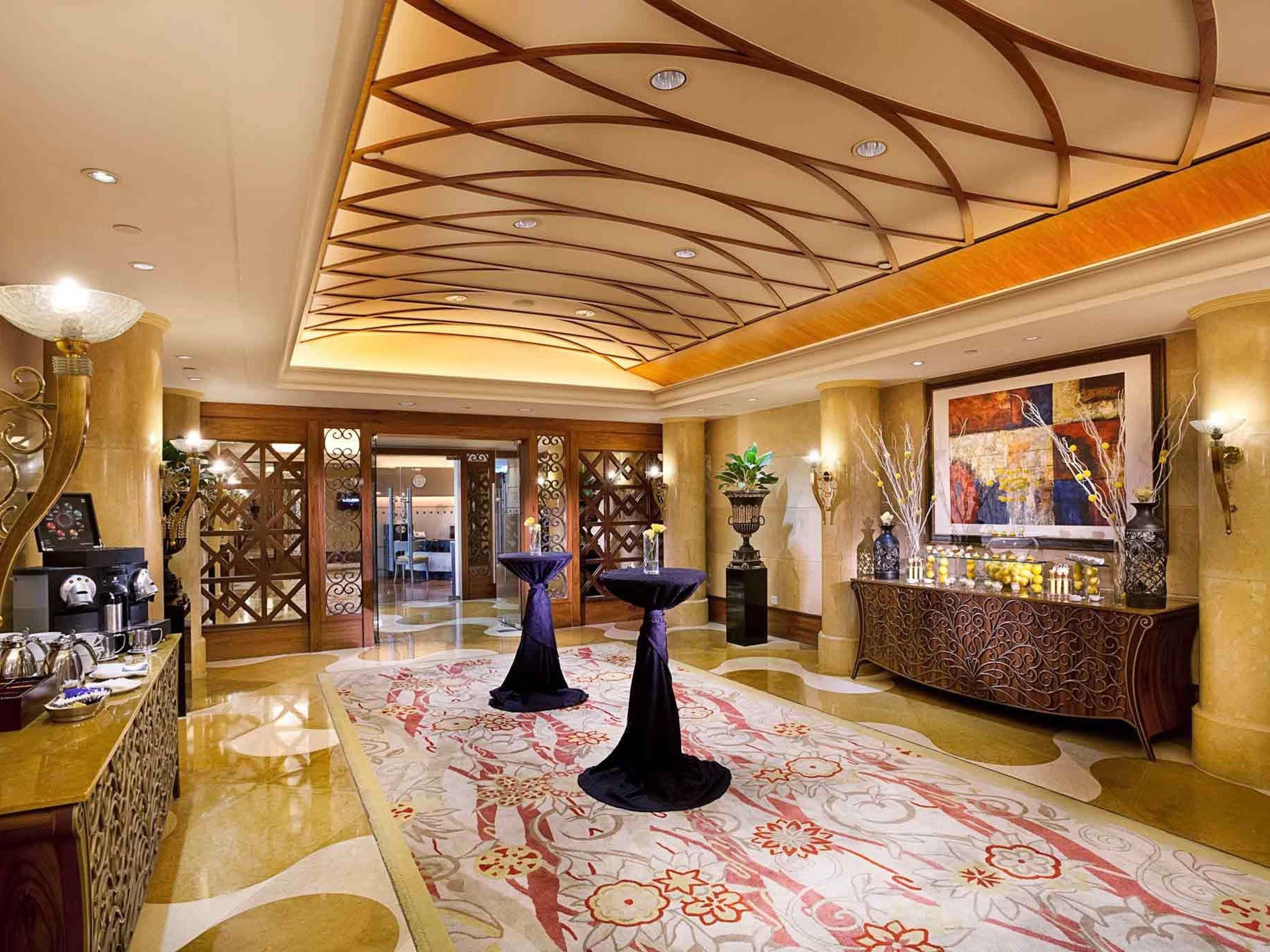 Een hotel lobby met een kamerbreed tapijt, een bar en een decoratief plafond.