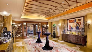 Een hotel lobby met een kamerbreed tapijt, een bar en een decoratief plafond.