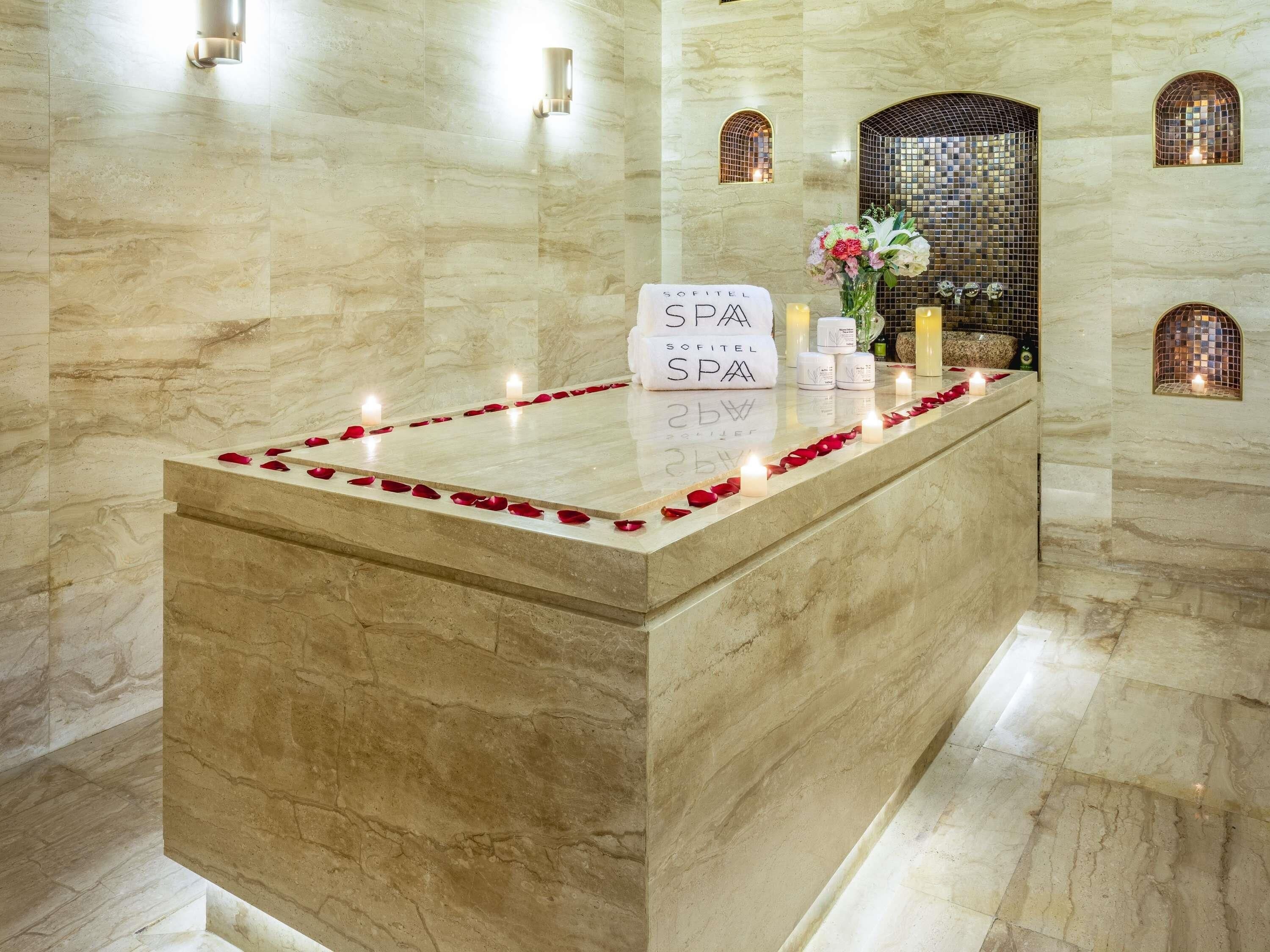 A reception area with a marble counter, a sign reading 'SOFITEL SPA,' and a decorative arrangement of candles and flowers.