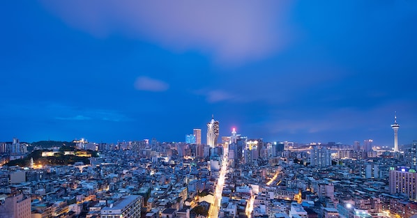 Une vue d’une ville au crépuscule, avec d’imposants gratte-ciel, une tour dotée d’une flèche distinctive et une tour à haubans.