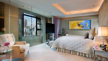 Quarto de hotel moderno com uma cama grande, divisória de vidro, televisão de tela plana e vista para a cidade.