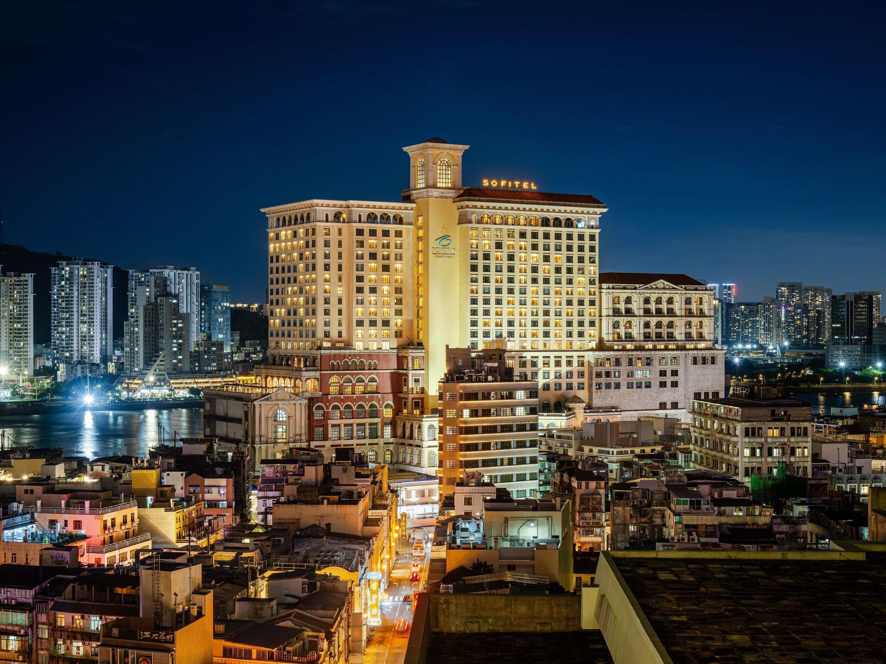 A high-rise hotel with multiple floors, a prominent tower, and a well-lit facade.