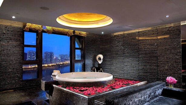 A modern bathroom with a large bathtub, a view of a cityscape, and a unique textured wall design. - Sofitel Macau At Ponte 16 (Macau)