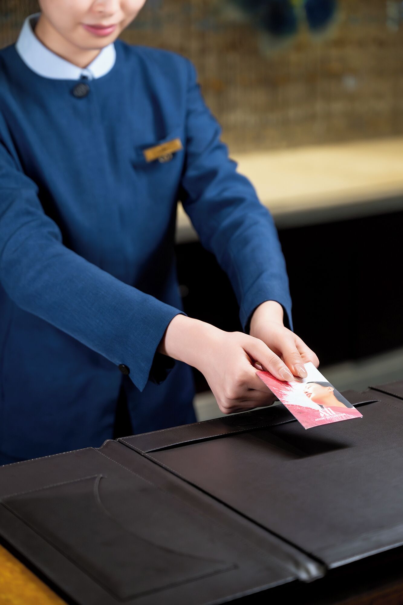 A person in a blue uniform handling a card at a table with a black surface.