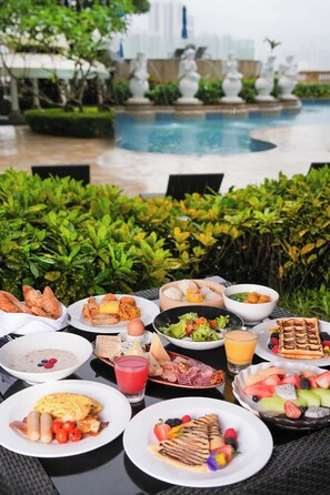 A table set with various breakfast items and a pool in the background. - Sofitel Macau At Ponte 16 (Macau)
