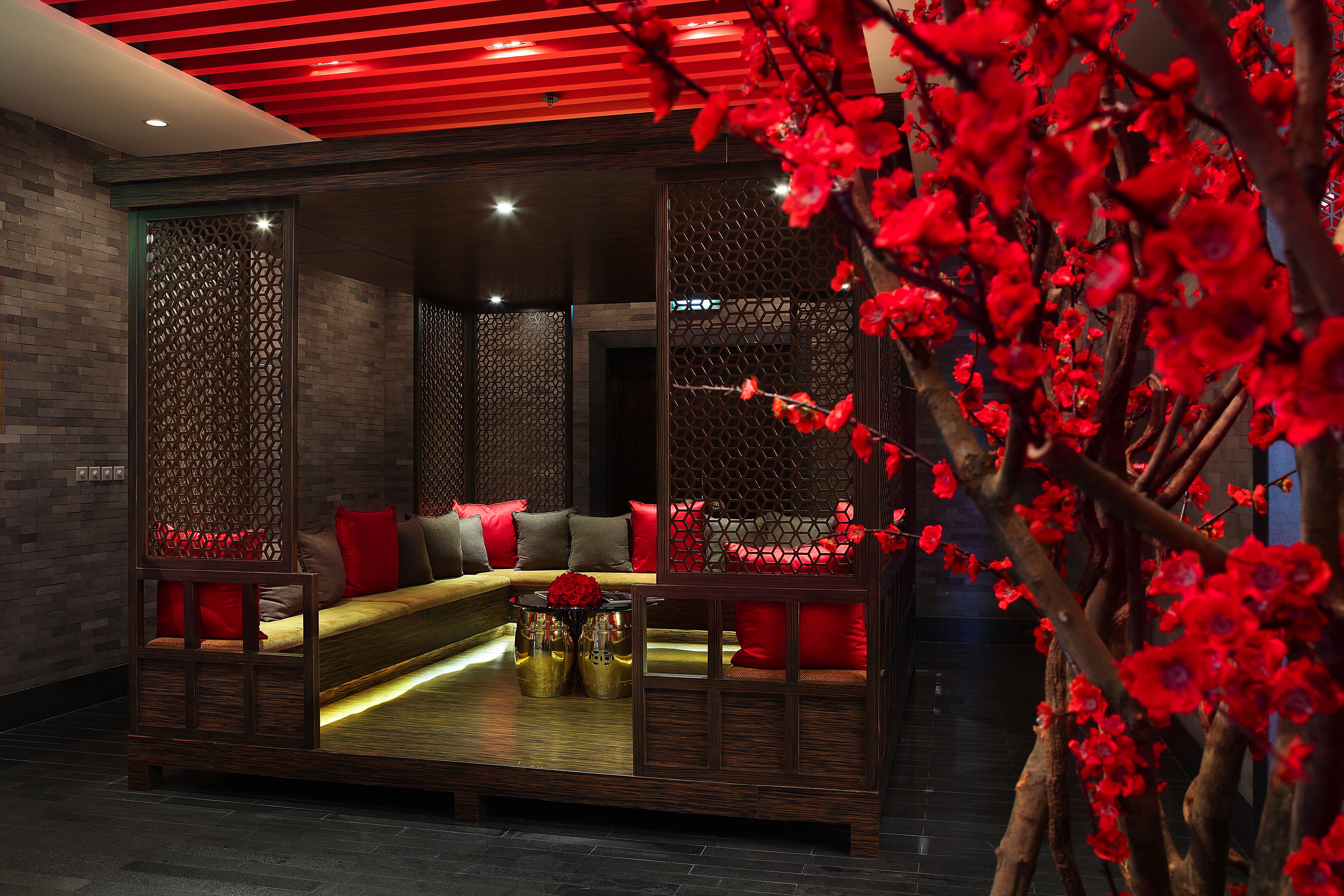 A modern interior with a sofa set, decorative panels, and a red floral arrangement.