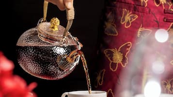 Een hand giet thee uit een decoratieve theepot in een kopje.