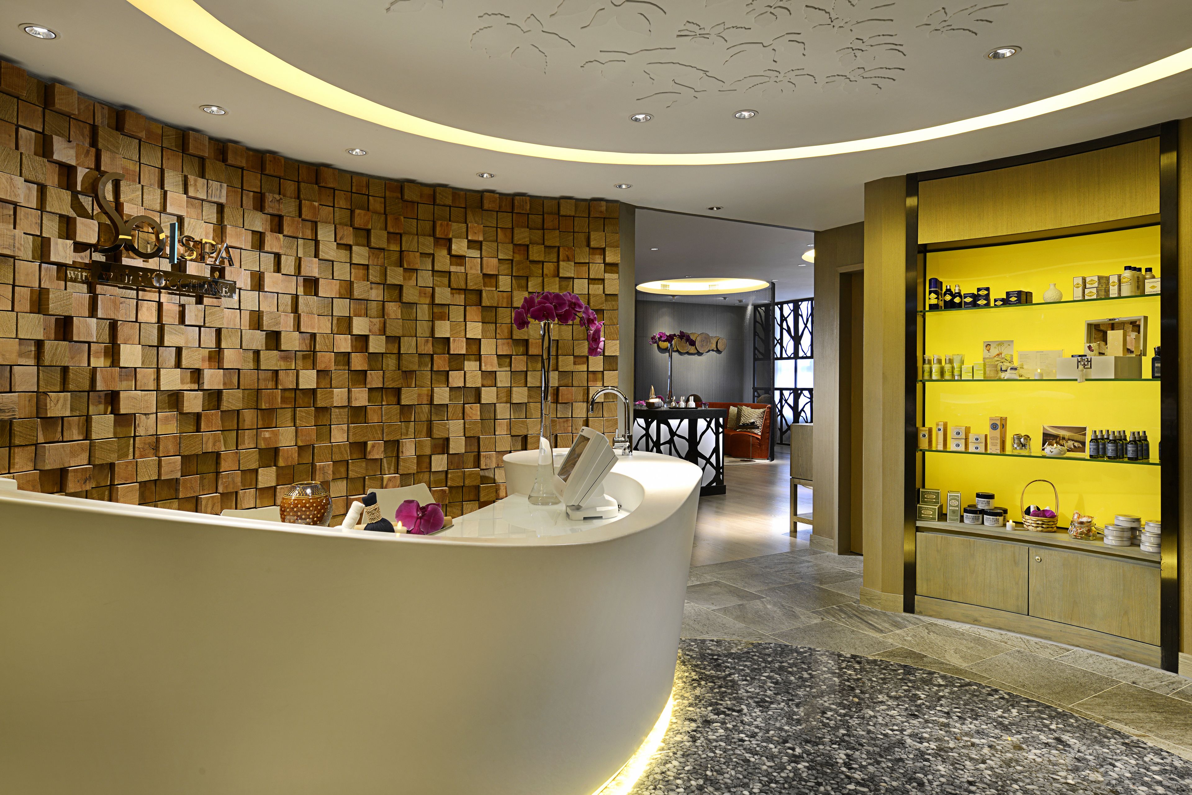 A reception area with a wooden wall, a reception desk, and a display of toiletries.