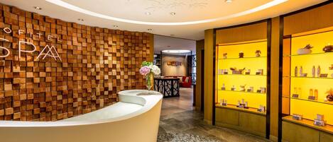A reception area with a wooden wall, a reception desk, and a display of spa products.
