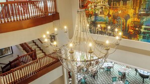 A multi-level hotel interior with a grand chandelier, wooden staircases, and a dining area with tables and chairs. - Hemingways Hotel  (East London)