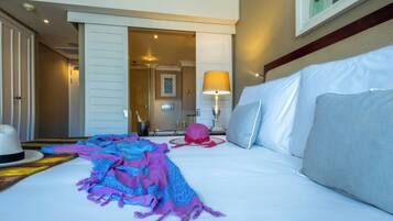 A hotel room with a bed, a nightstand, a lamp, and a door leading to another room.