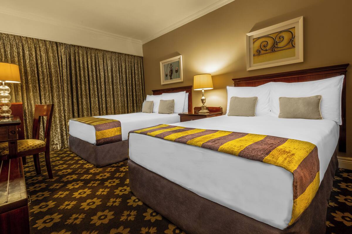 A hotel room with two beds, a desk, and a chair.