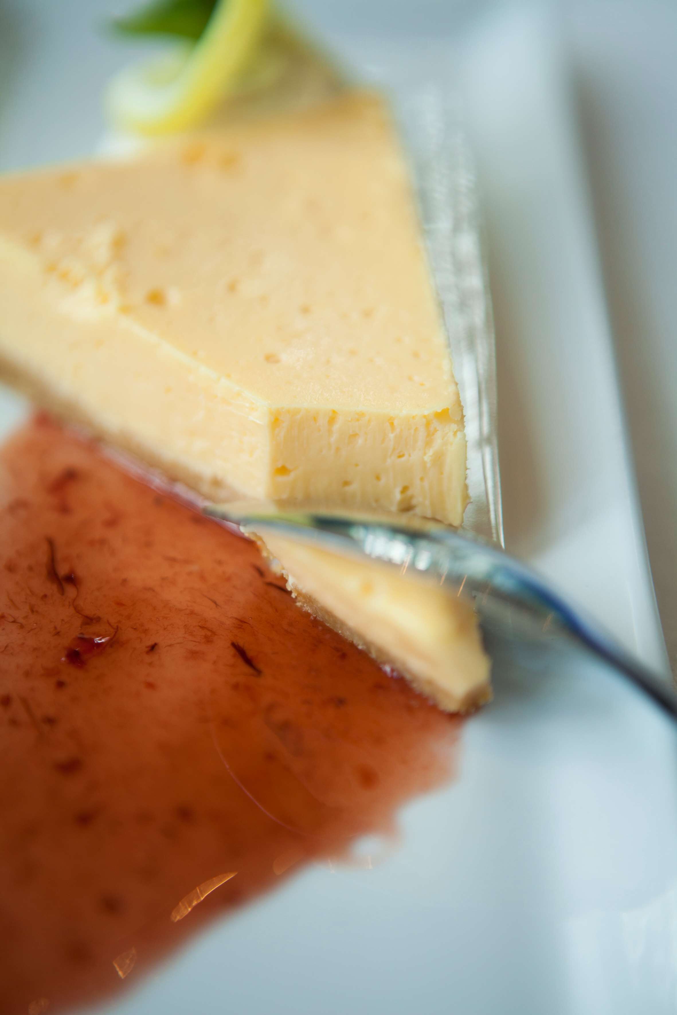 Ein Stück Käsekuchen auf einem weißen Teller mit einer Erdbeere.