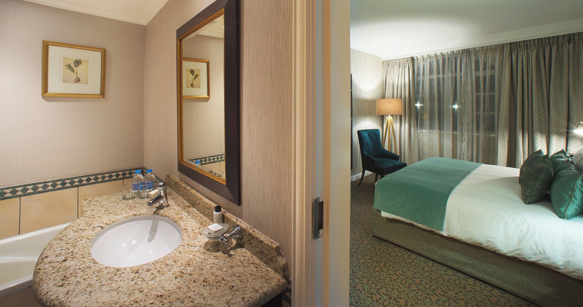 Une salle de bain d’hôtel avec un lavabo, un miroir et une œuvre d’art botanique encadrée accrochée au mur.