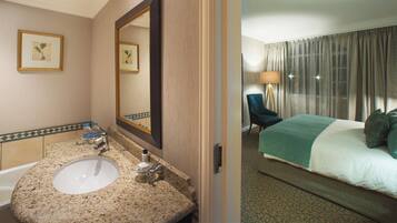 Une salle de bain d’hôtel avec un lavabo, un miroir et une œuvre d’art botanique encadrée accrochée au mur.