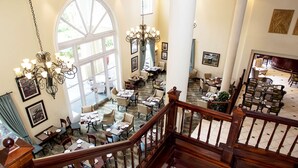 A hotel lobby with multiple dining areas, a grand staircase, and large windows allowing natural light. - Southern Sun Mbombela (Mbombela)