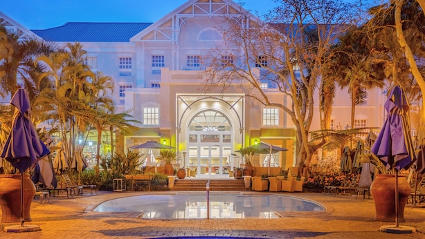 A hotel with a large pool, outdoor seating, and a grand entrance. - Southern Sun Mbombela (Mbombela)