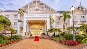 A hotel with a grand entrance, a red carpet, and lush tropical landscaping. - Southern Sun Mbombela (Mbombela)