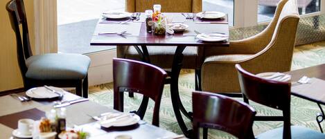A dining area with a table set for four, including plates, cutlery, and a small vase with flowers.