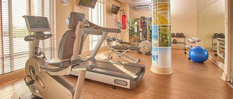 Un gimnasio con máquinas de cardio, pesas y pelotas de ejercicio.
