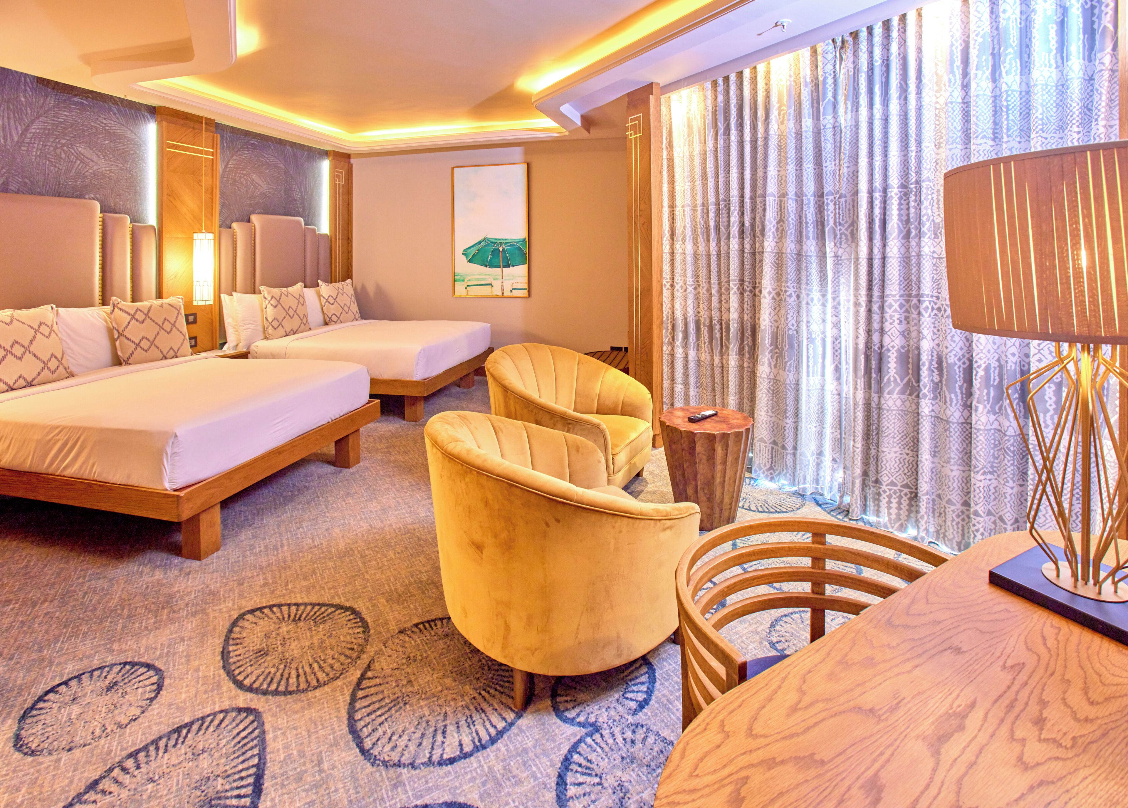 A hotel room with two beds, a sofa, a round table, and a lamp.