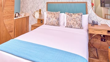 Een hotelkamer met een groot bed, een houten dressoir, een bureau met telefoon en een spiegel.