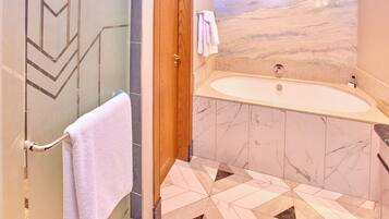 Un baño con pared de mármol, una bañera y suelo de baldosas geométricas.