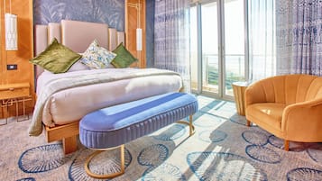 A hotel room with a bed, a bench, a chair, a large window, and a patterned carpet.
