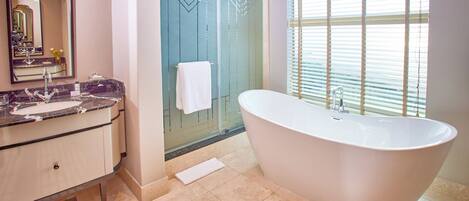 A modern bathroom with a freestanding bathtub, a glass shower enclosure, and a vanity with a marble countertop.