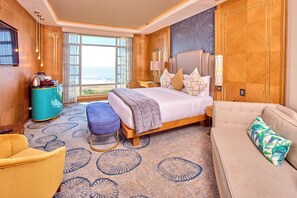 A hotel room with a large bed, a sofa, a small table, a chair, and a view of the ocean. - Suncoast Hotel & Towers (Durban)