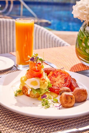 A breakfast plate with eggs, tomatoes, and greens, a glass of orange juice, and a vase with flowers. - Suncoast Hotel & Towers (Durban)