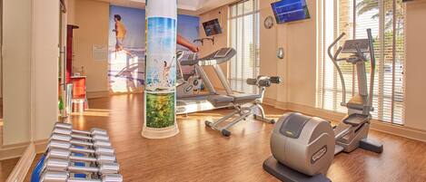Un gimnasio con equipo de ejercicio, un pilar grande y un mural en la pared.