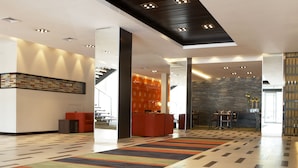 A spacious lobby with a modern design, featuring a patterned floor, a reception area, and a seating area with a red sofa. - Southern Sun Newlands (Cape Town)